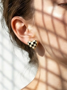 Gros plan d'une boucle d'oreille cœur à damier noir et blanc avec des bords dorés