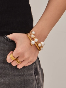 Detalle de brazalete abierto bañado en oro 18k con perlas naturales y anillo floral retro
