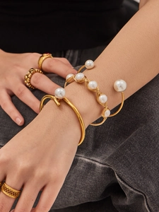Detalle de brazalete abierto bañado en oro de 18k con perlas naturales sobre denim