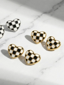 Gros plan de boucles d'oreilles cœur émaillées à damier sur fond de marbre blanc
