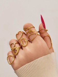Close-up of gold geometric heart rings stacked on fingers with crystal details