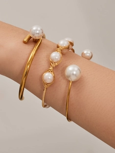 Detalle de tres pulseras de perlas bañadas en oro de 18k en la muñeca de modelo