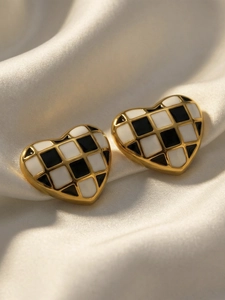 Gros plan sur des boucles d'oreilles cœur à damier en émail et bordure en métal doré