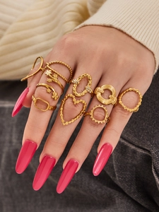 Detail of bohemian gold stackable rings set with floral and heart shapes on a model