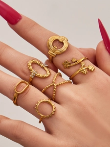 Detail shot of six gold geometric rings with floral and rhinestone accents on hand