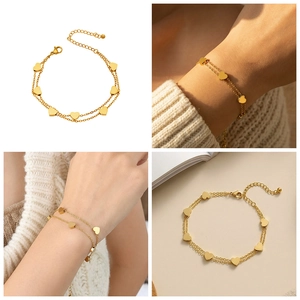 Detail of double-layer gold chain bracelet featuring heart charms and lobster clasp