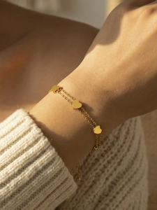 Detail of 18k gold-plated double-layer chain bracelet featuring three polished heart charms