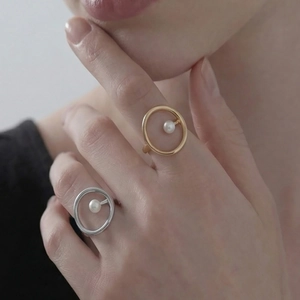Minimalistische 18K Gold- und Silberringe mit schwebender Perle an einer Frauenhand