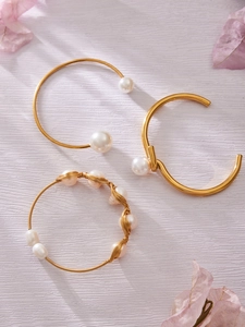 Detalle de brazaletes bañados en oro 18k con perlas naturales sobre fondo lila suave