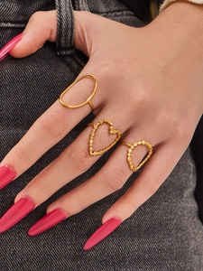 Detailed view of gold stainless steel geometric heart rings set on a denim background