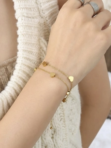Double-layered gold chain bracelet with polished heart charms on model wrist