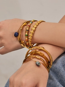 Bracelets dorés superposés avec perles tête de mort, émail et pendentifs en pierre naturelle