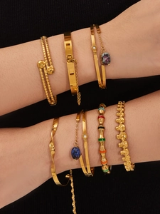 Détail de bracelets dorés empilés avec pierres naturelles et touches d'émail coloré