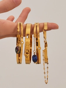 Détail de quatre bracelets dorés avec des pendentifs en pierres naturelles violettes