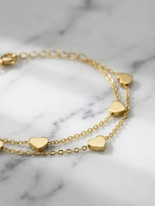 Macro detail of 18k gold plated double-layer heart charm bracelet with lobster clasp