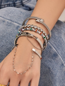 Gros plan de bracelets argentés empilés aux motifs punk et serpent sur du denim
