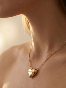 Dettaglio della collana con pendente a cuore dorato e incisione del battito cardiaco su modella