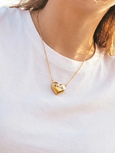 Dettaglio della collana con cuore ECG dorata indossata da una modella su t-shirt bianca