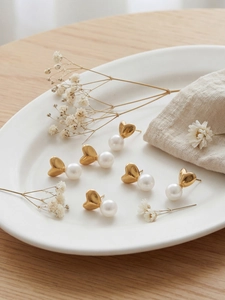 Détail de boucles d'oreilles cœur en or 18k avec perles sur une surface en bois