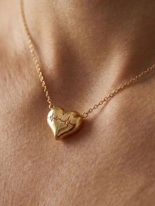 Dettaglio della collana a cuore dorata con incisione di battito cardiaco rosso su modella
