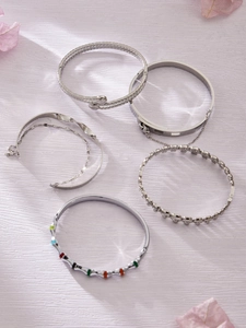 Détail de cinq bracelets en acier inoxydable argenté avec textures variées et pierres colorées