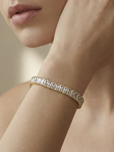 Detailopname van een vergulde tennisarmband met rechthoekig geslepen zirkoniasteentjes