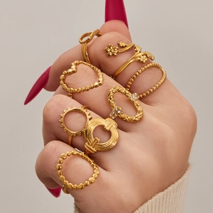 Geometric gold ring set featuring heart and floral designs on model's hand