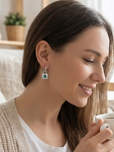 Gros plan d'une boucle d'oreille cadenas argentée avec pierre verte sur un mannequin