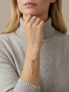Adjustable gold snake chain bracelet featuring a bolo closure and polished metal beads