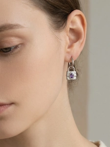 Gros plan de boucles d'oreilles cadenas argentées avec pendentif zircon violet