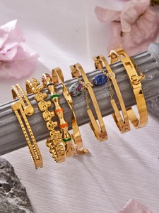 Détail de bracelets dorés avec pierres précieuses et émail sur décor en pierre