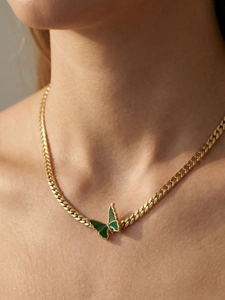 Close-up of a 18k gold-plated Cuban chain necklace featuring a green butterfly pendant