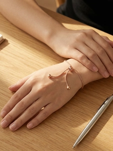 Detail of rose gold snake chain bracelet featuring adjustable drawstring bead closure