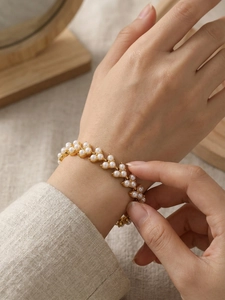 Gros plan d'un bracelet de perles dorées en forme de feuilles sur le poignet d'une femme