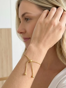 Detail of adjustable gold snake chain bracelet with bolo clasp and solid beads on wrist