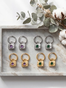Détail de boucles d'oreilles cadenas serties de zircons violets et verts
