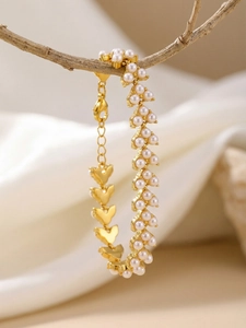 Détail du bracelet cœur plaqué or 18 carats avec perles suspendu à une branche en bois