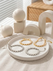 Détail de bracelets en perles tissées avec maillons or et argent sur plateau céramique