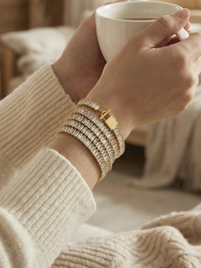 Dettaglio del bracciale a catena in oro con zirconi e chiusura a T sul polso