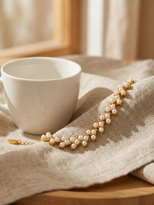Détail du pendentif S925 sur bracelet perles dorées posé sur un tissu en lin fin