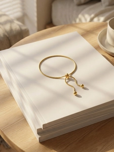 Detail of adjustable gold bolo snake chain bracelet on a minimalist white book stack