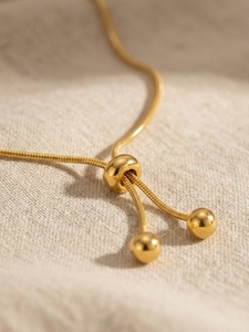 Detail of adjustable gold snake chain with a spherical slide clasp and bead charms