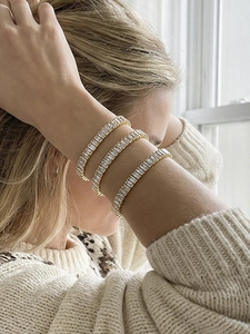 Dettaglio di bracciali tennis placcati in oro con zirconi rettangolari indossati al polso