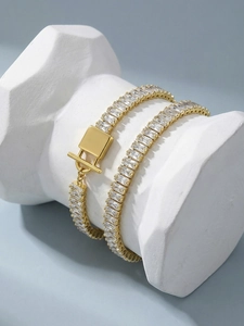 Dettaglio bracciale placcato oro con zirconi a baguette e chiusura a T su marmo
