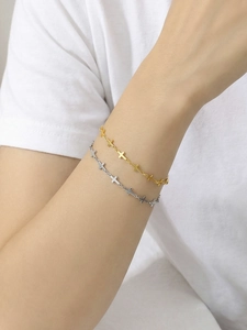 Macro detail of gold and silver cross link bracelets on wrist for trendy daily wear