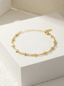 Detailed macro view of golden cross bracelet with lobster clasp and adjustable chain link