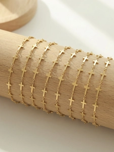 Detailed view of golden cross link bracelets on a natural wood display stand