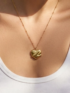 Detailed view of irregular 3D gold heart pendant with beaded chain on model