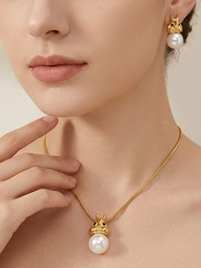 Détail d'un pendentif écureuil doré avec perle et boucles d'oreilles sur un mannequin