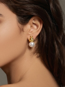 Détail de boucles d'oreilles écureuil avec tête dorée et perle blanche élégante
